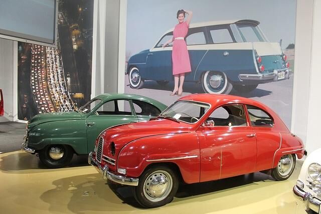 Saab 92 (ab 1950) und Saab 93 vor Werbeplakat von Saab 95 Kombi 