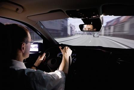Der Testfahrer nimmt in einem Auto Platz, rundherum wird auf einer 360-Grad-Projektionswand Straßengeschehen realitätsgetreu nachgestellt.