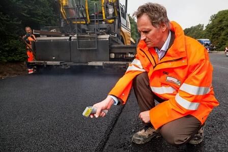 Damit die Fahrbahn einen soliden Neubelag bekommt, messen Straßenbauer beim Asphaltieren die Temperatur des Gestein-Gemischs. (Bild: Straßen NRW)
