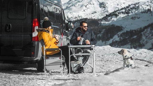 Wer beim Wintercamping die richtige Kleidung hat, kann auch bei Kälte die Sonne vor dem Wohnmobil genießen