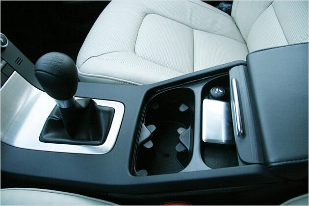 Unter einer beweglichen Abdeckung befinden sich Getränkehalter und ein Aschenbecher