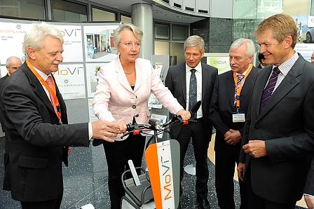 Strampeln für die Fotografen - auch der Elektroroller interessiert die Forschungsministerin.