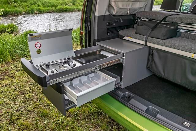 Während der Küchenblock im kurzen Caddy hinten mit dem darüberliegenden Bett direkt an der Heckklappe abschließt, entsteht bei der Langversion zwischen dem Kopfteil des Betts und der Heckklappe...